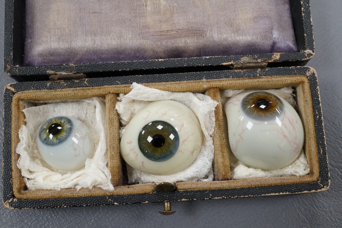 A late 19th century cased group of three prosthetic glass eyes